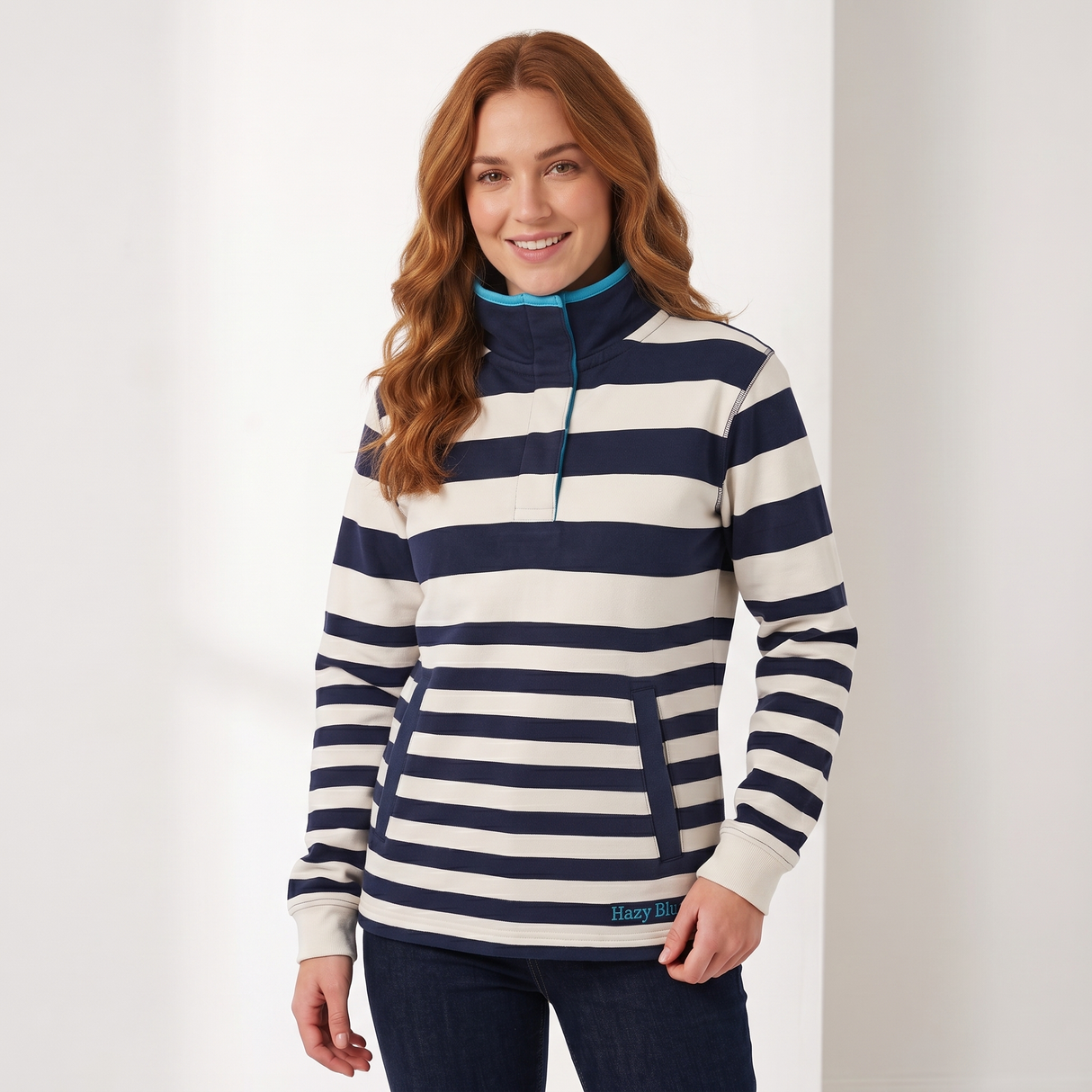 A woman modeling a navy and cream horizontally striped quarter-zip pullover sweater with a bright blue inner collar and zipper trim, paired with dark blue jeans against a clean white studio background.