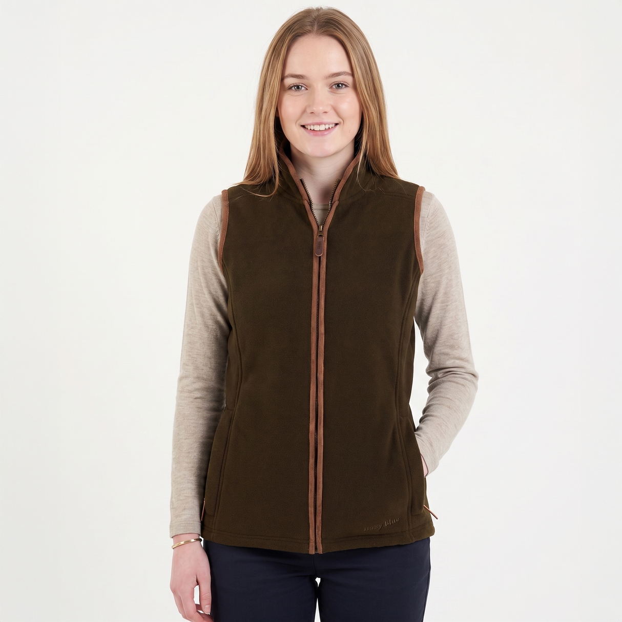 Woman wearing a brown vest over a beige long-sleeve shirt on a white background