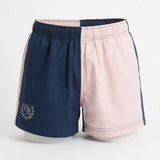 A pair of split-color shorts with one side in navy blue and the other in light pink, featuring a white embroidered monogram logo on the navy side and piping details, displayed on a white mannequin against a white background.