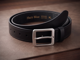 Black leather belt with silver buckle on a brown surface
