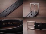 Black leather belt with silver buckle on a wooden surface