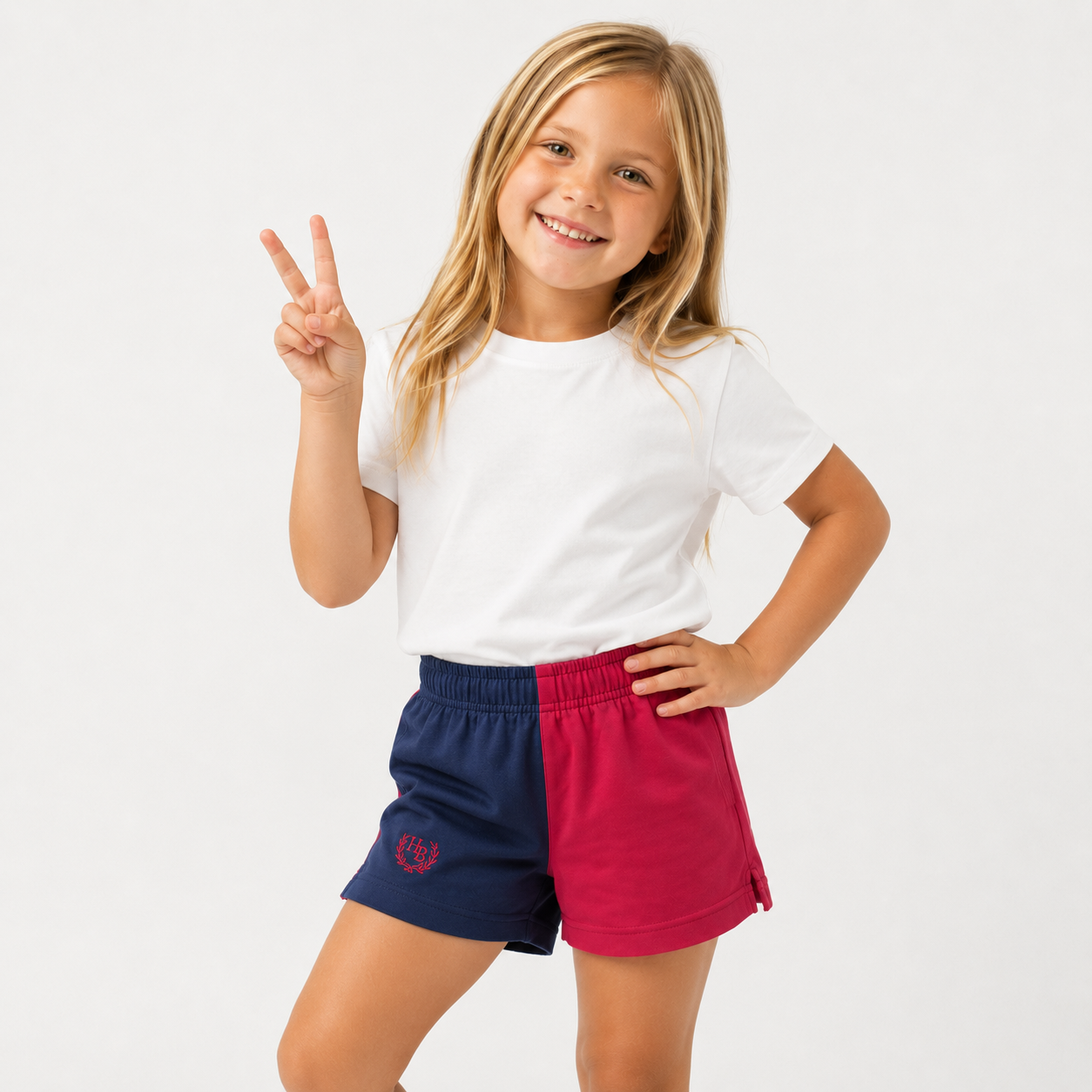 Young girl wearing a white t-shirt and red and blue shorts on a white background
