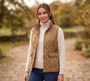 Woman wearing a beige quilted vest outdoors with a blurred natural background
