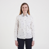 A woman modeling a white long-sleeve button-up shirt with a small black bow pattern, paired with dark navy pants, against a plain white studio background.