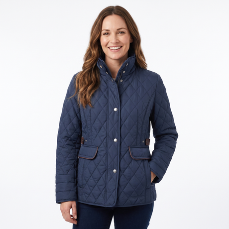 A woman wearing a navy blue diamond-quilted jacket with brown trim and silver snap buttons, standing against a plain white studio background.