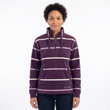 A woman modeling a purple half-zip fleece pullover with white horizontal stripes, featuring a drawstring neck and a small 'Hazy Blue' brand logo near the bottom right hem, set against a plain white background.