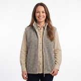 A woman modeling a gray zip-up fleece vest over a beige and brown checkered button-down shirt, photographed against a plain white studio background.