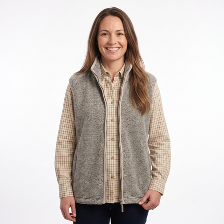A woman modeling a gray zip-up fleece vest over a beige and brown checkered button-down shirt, photographed against a plain white studio background.