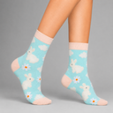 A pair of ankle socks worn on a model's legs, featuring a light blue background with white rabbits, daisies, and clouds, finished with pale pink ribbed cuffs and heels.