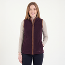 Woman wearing a purple vest over a beige long-sleeve shirt on a white background