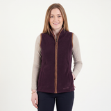 Woman wearing a purple vest over a beige long-sleeve shirt on a white background