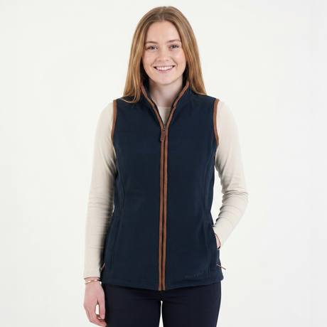 Woman wearing a navy blue vest with brown accents on a white background