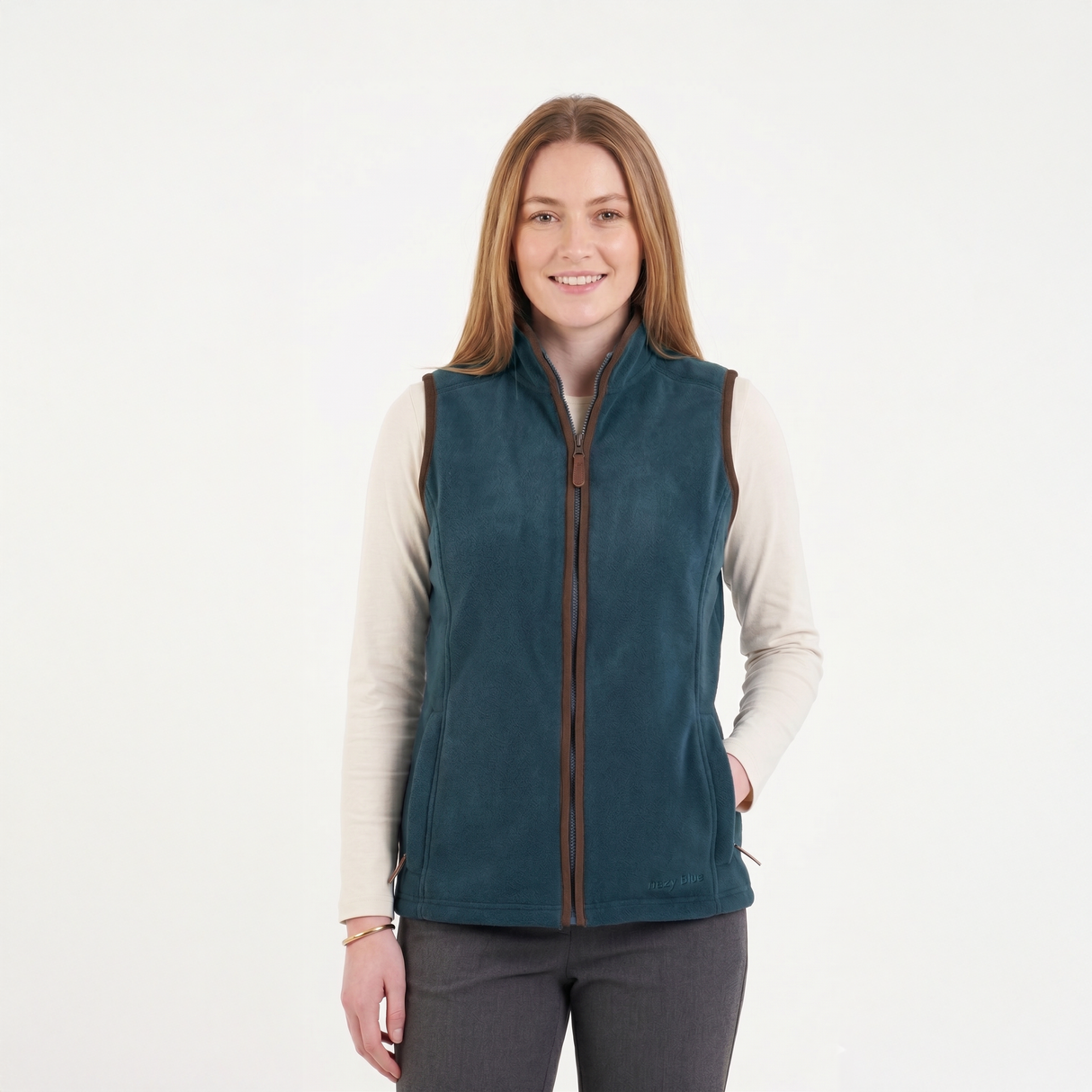 Woman wearing a teal vest over a cream shirt on a white background