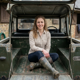 Woman sitting in the back of a vintage Land Rover vehicle.