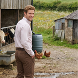 Man standing on a farm with chickens and a barn in the background
